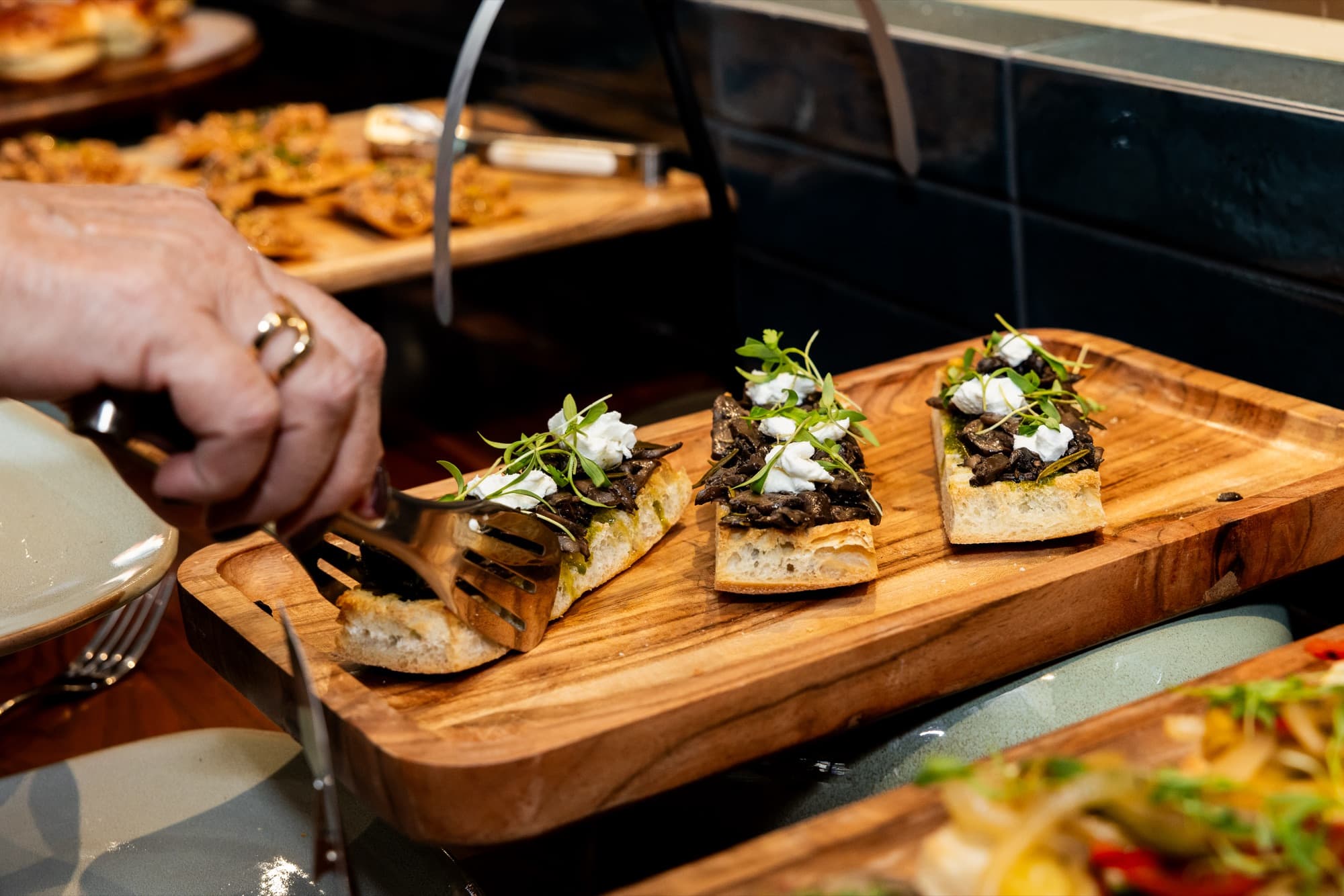 Crostini bites served on wooden boards at a Cotidiano event