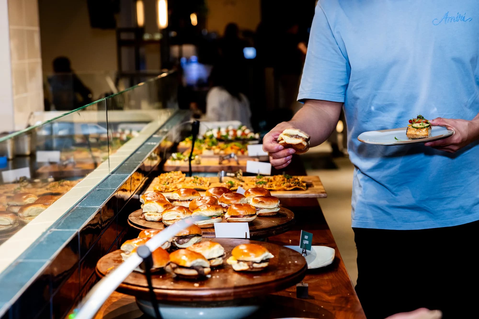 A guest selecting small bites from a Cotidiano catering spread