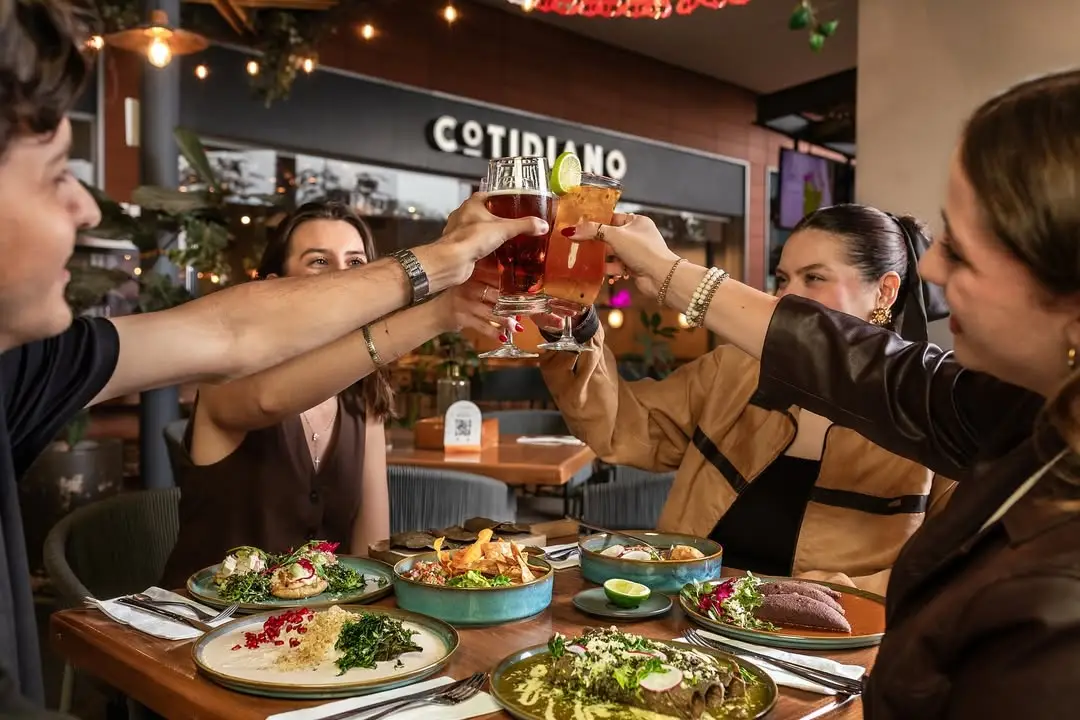 Friends raising a toast over a shared meal at Cotidiano