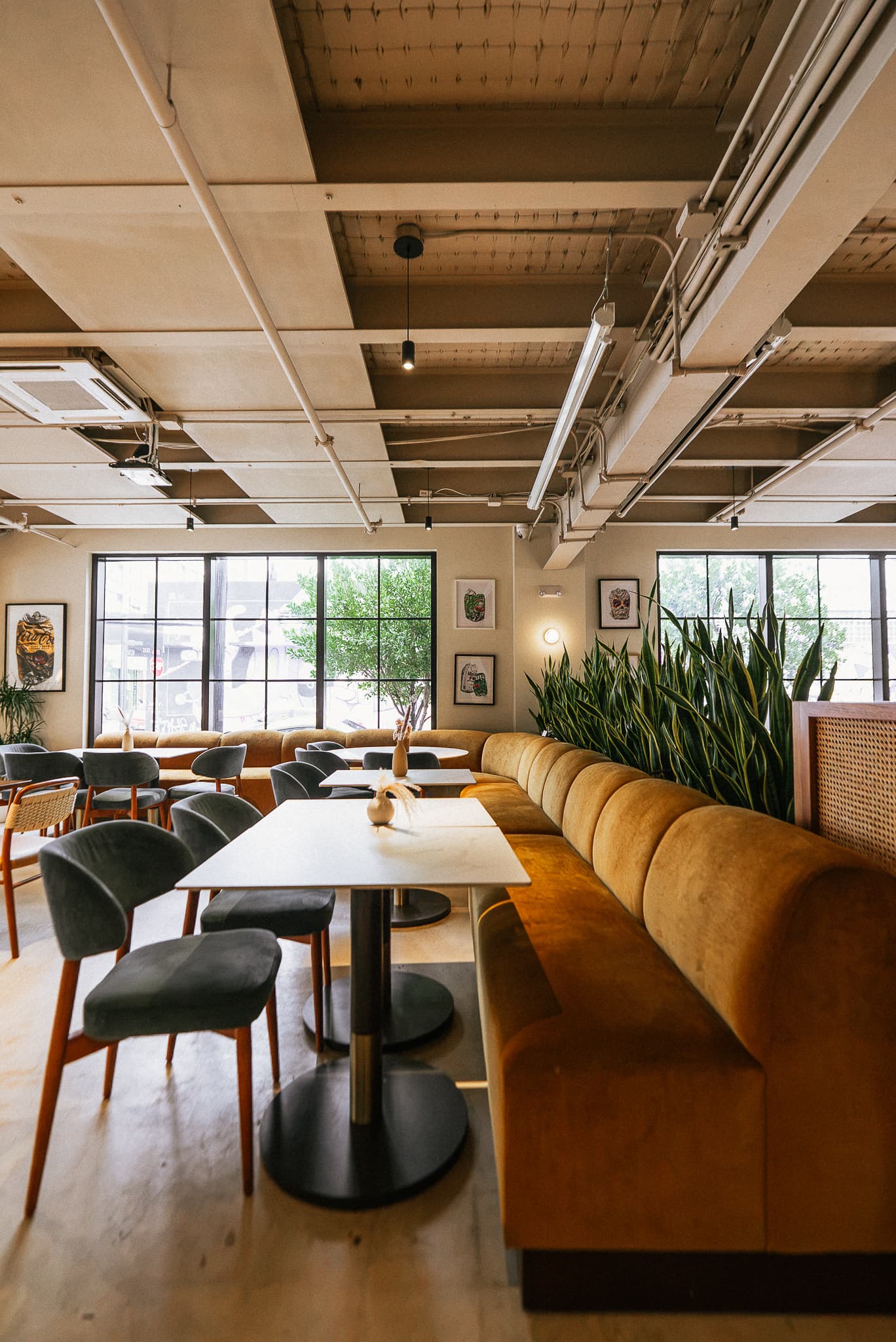Sunlit Cotidiano dining room with upholstered banquettes and tables